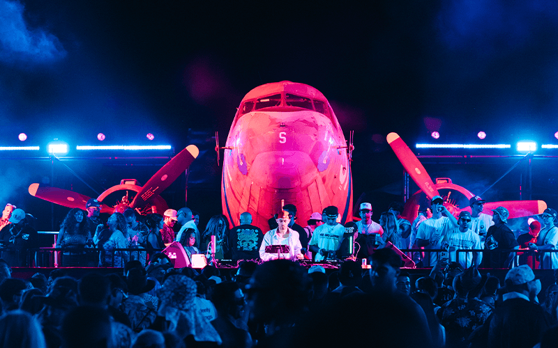 Splash House After Hours crowd dancing beneath a pink-lit aircraft in Palm Springs.