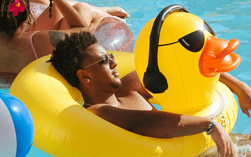 Splash House guest relaxing in a yellow duck float in a Palm Springs pool.